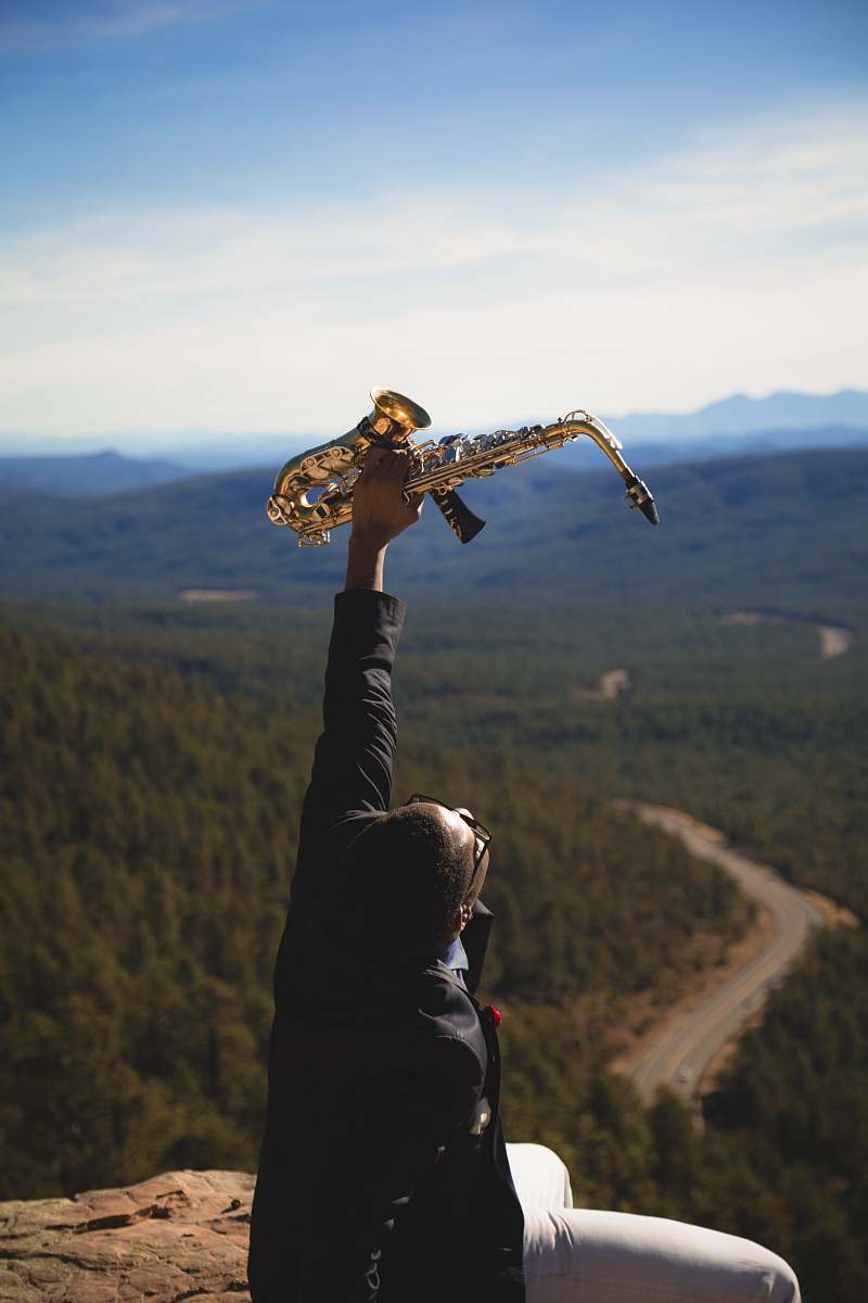 person person holding up brass-colored saxophone human