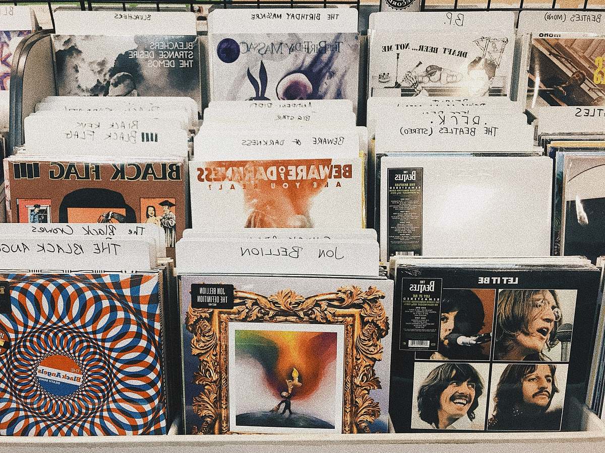 human pile of assorted-title vinyl album record sleeves person