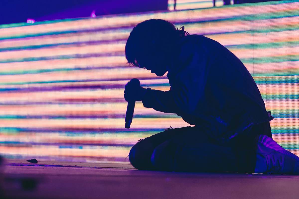 human silhouette photo of man sitting on stage while holding dynamic wireless microphone person