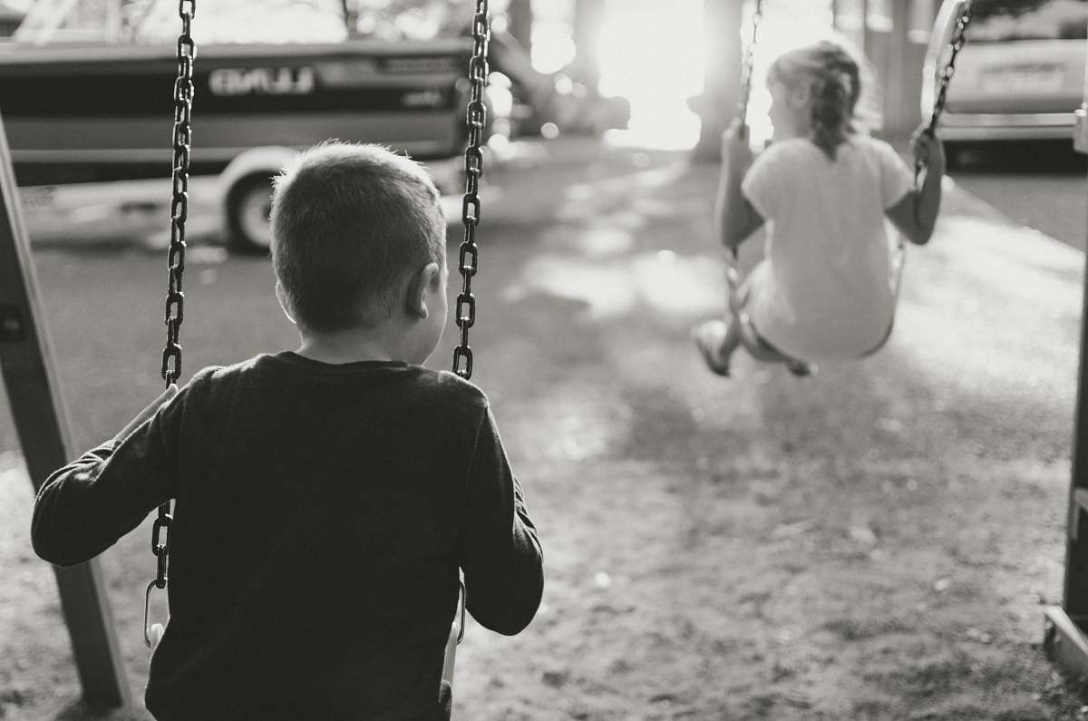 swing grayscale photography of boy and girl on swing toy
