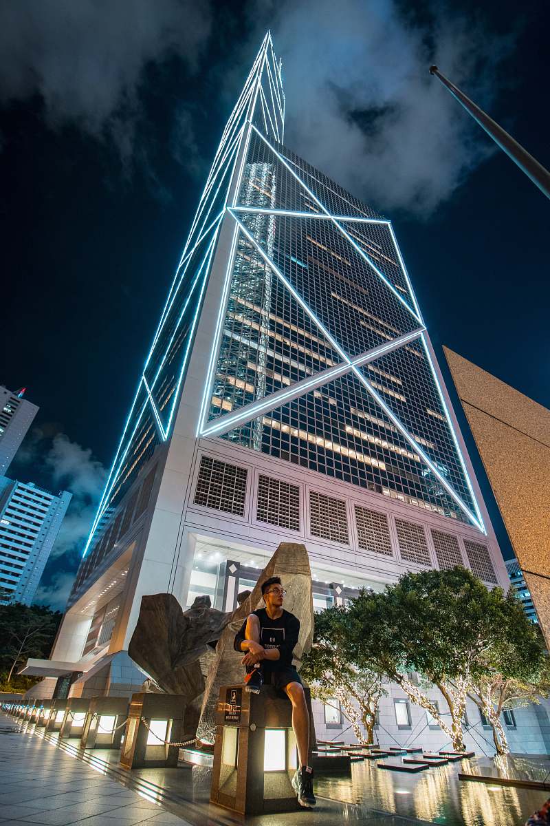 vase low angle photography of man seating in front of skyscraper tree