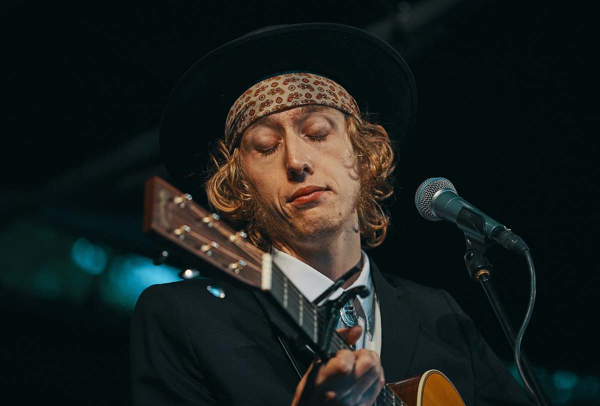 human man playing brown guitar people