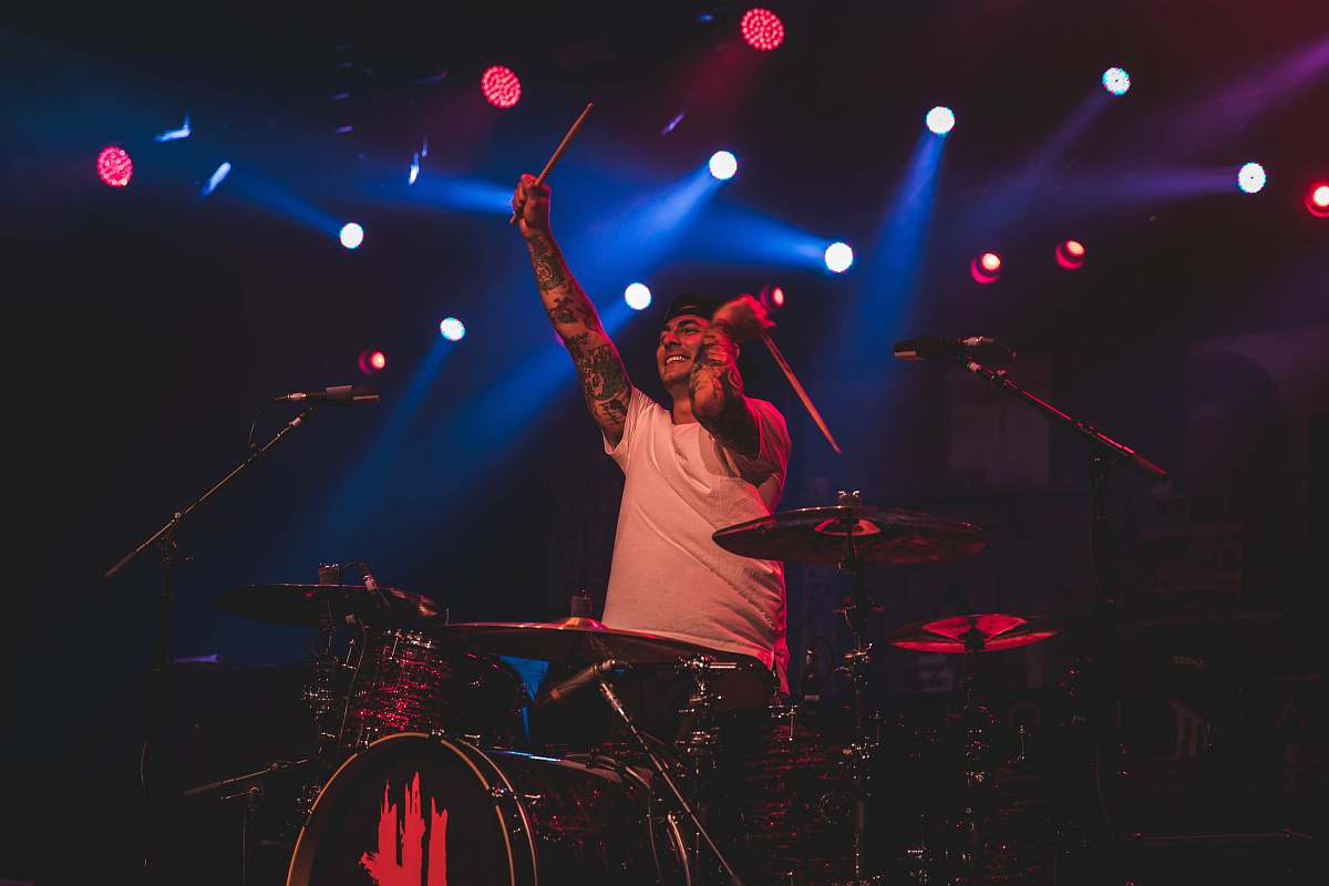 human man playing drums with spotlights people