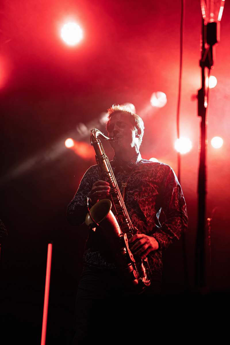 human man playing saxophone on stage crowd