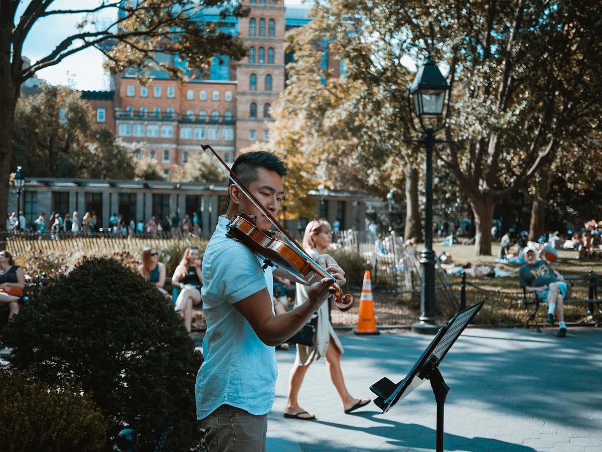 human man playing violin at the park people