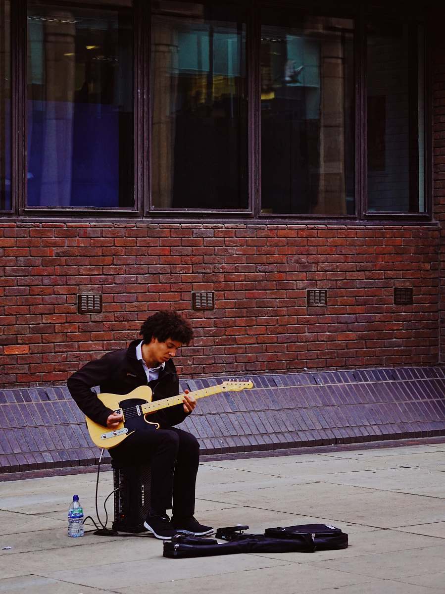 human man playing with his electric guitar while sitting on guitar amlplifier people