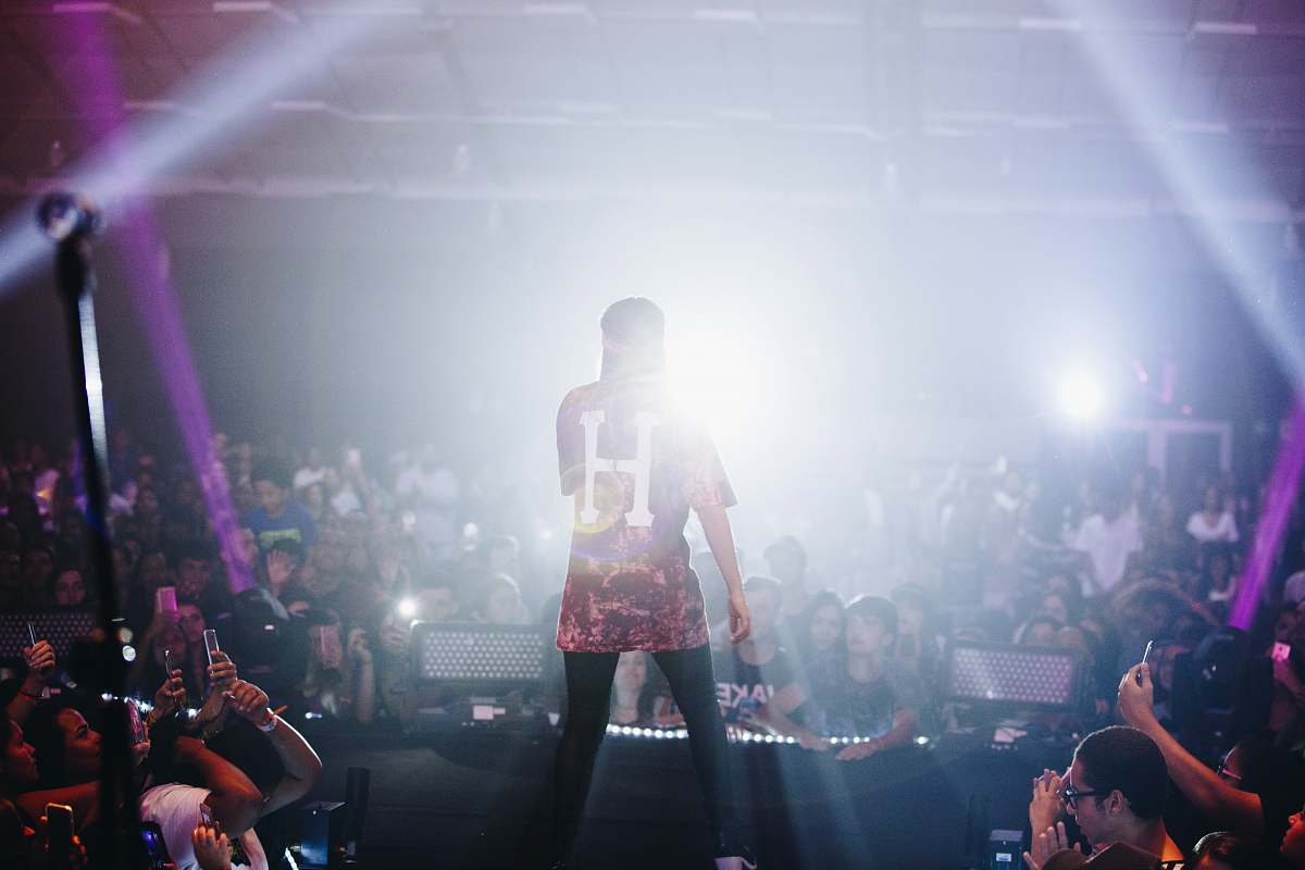 human man singing on stage in front of crowd people