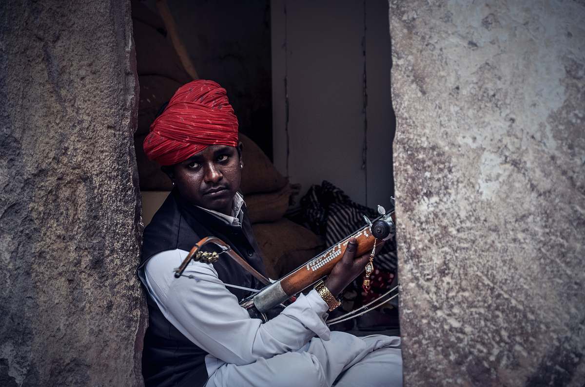 human man sitting beside gray concrete wall turban