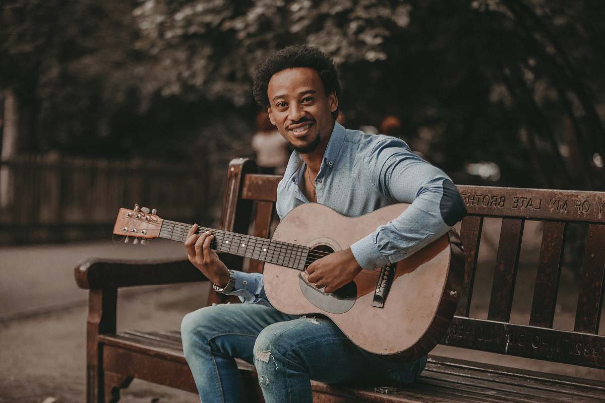 musician man sitting on bench playing guitar performer
