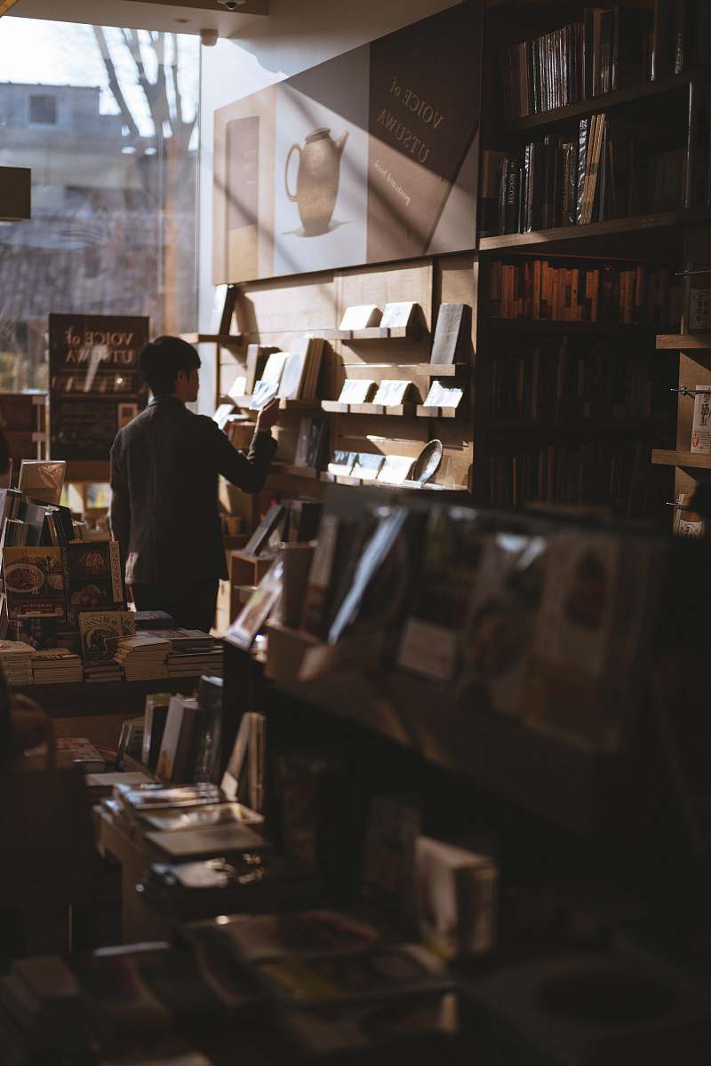 human man standing inside library finding books people
