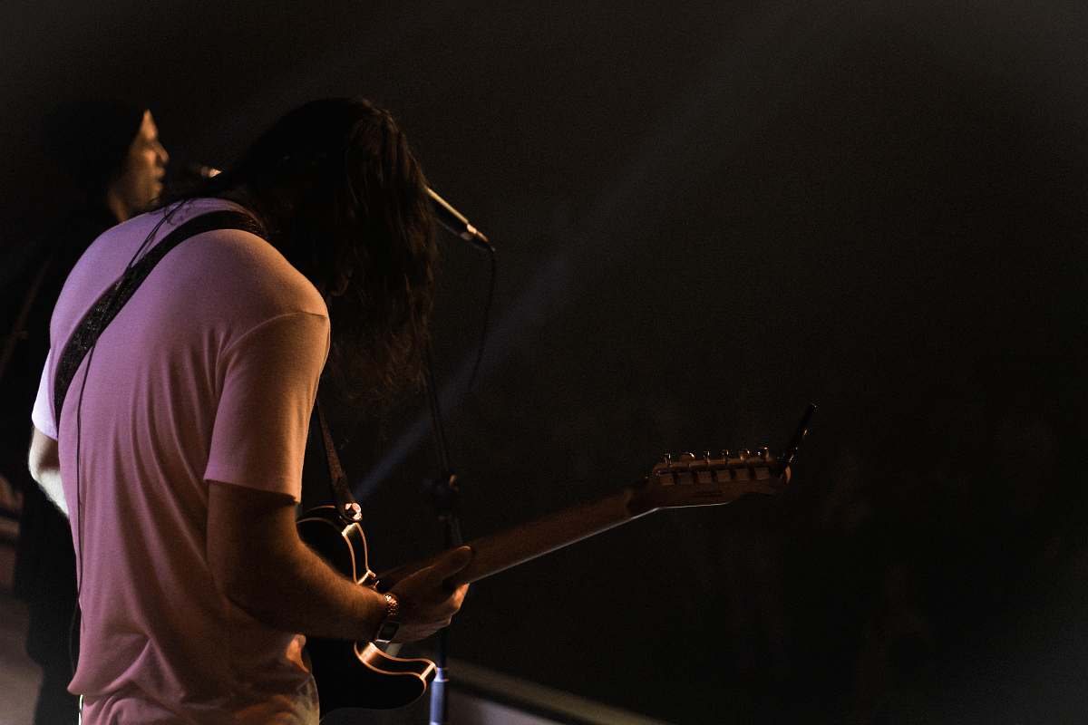 human man standing while playing guitar people