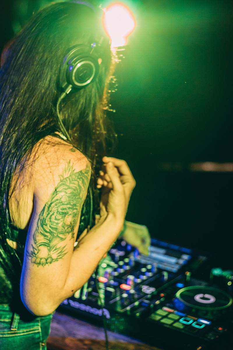human woman in green and black floral sleeveless dress wearing headphones skin