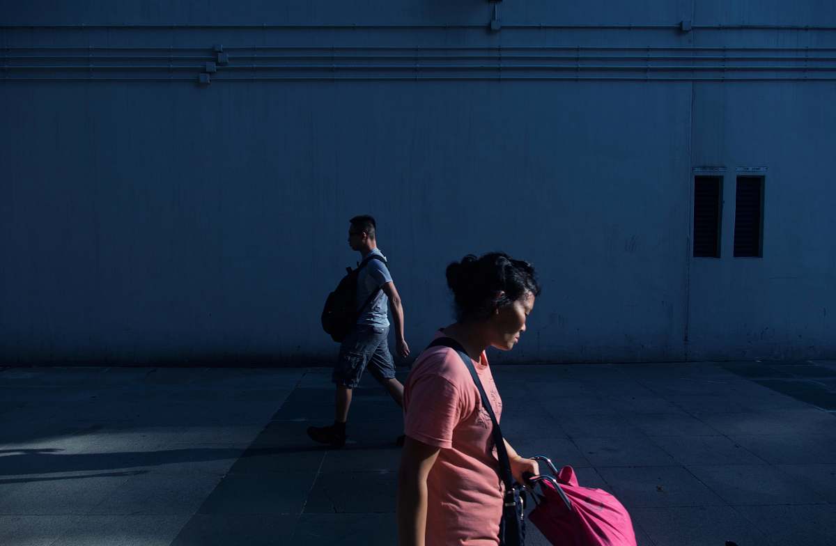 human woman walking near man beside white wall at daytime people