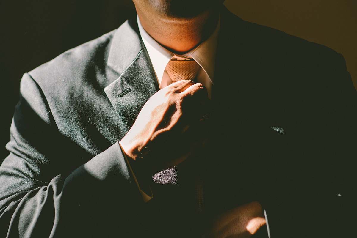 A Man In A Black Suit Loosening His Tie Image Free Photo