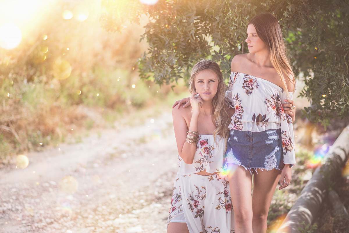  two women standing beside tree 