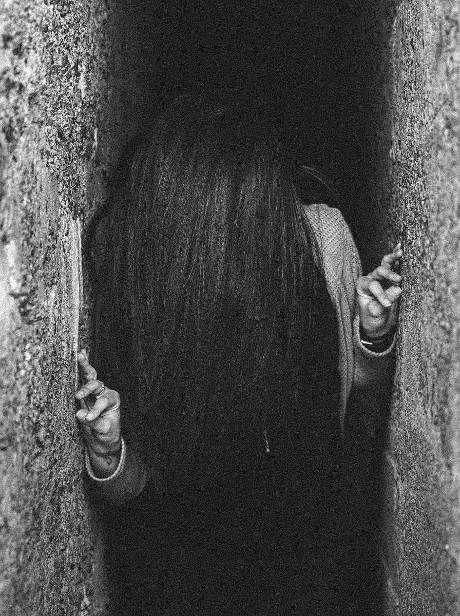 This striking image features a woman standing confidently in a hole between two gray concrete walls, creating a powerful visual contrast. The urban backdrop offers a unique setting that is perfect for artistic projects, editorial use, or advertising campaigns. Captured in an intriguing pose, this photograph evokes themes of isolation, resilience, and modern life in the city, making it a versatile choice for creatives seeking to convey strong narratives.