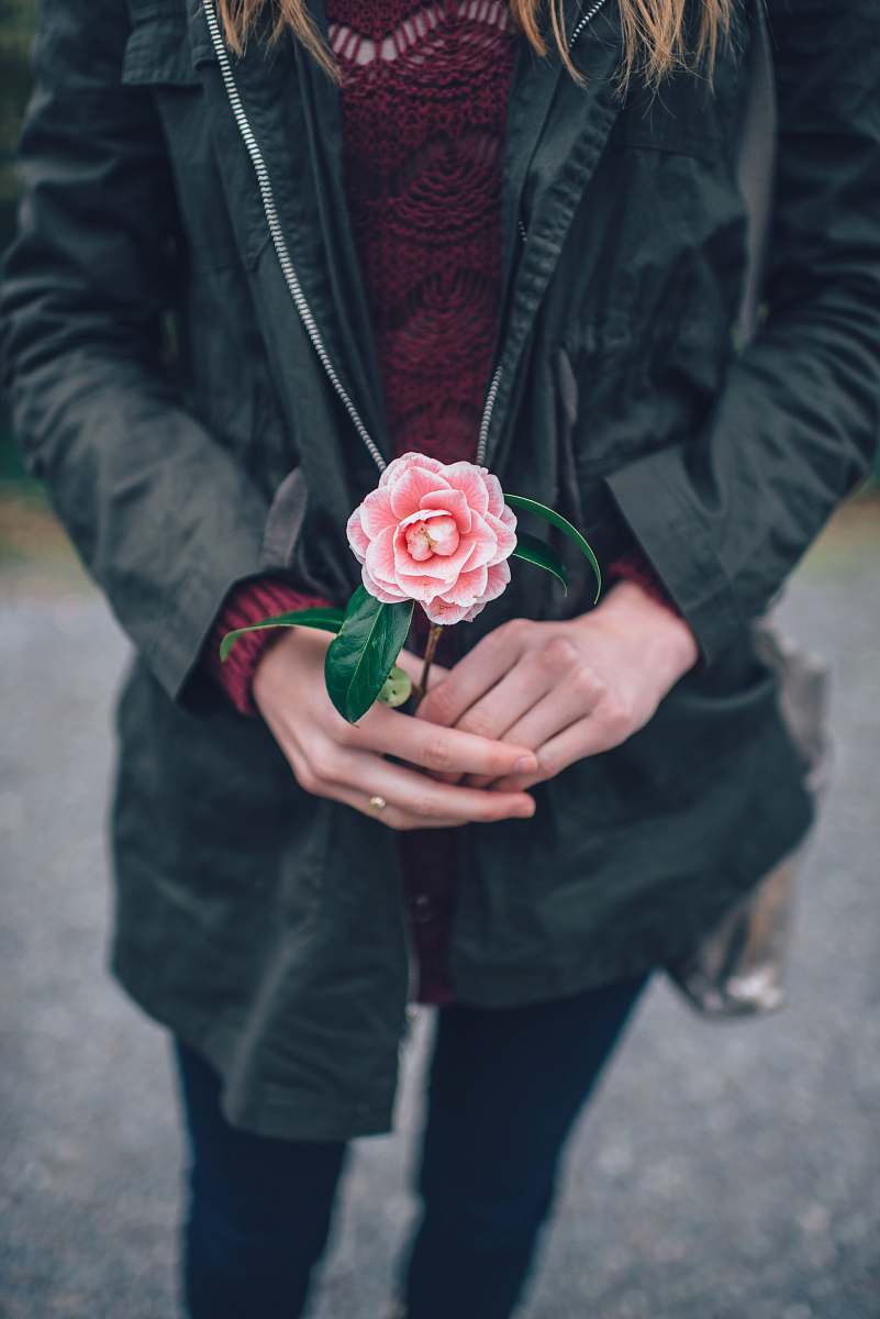 people woman in black leather jacket holding pink flower during daytime rose