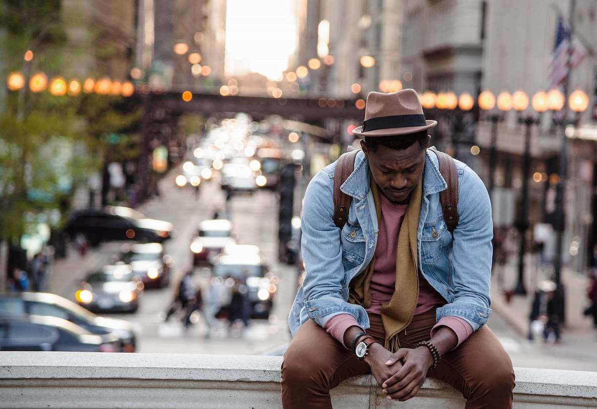 human A man in a leather jacket looking down while sitting on a ledge in a city chicago