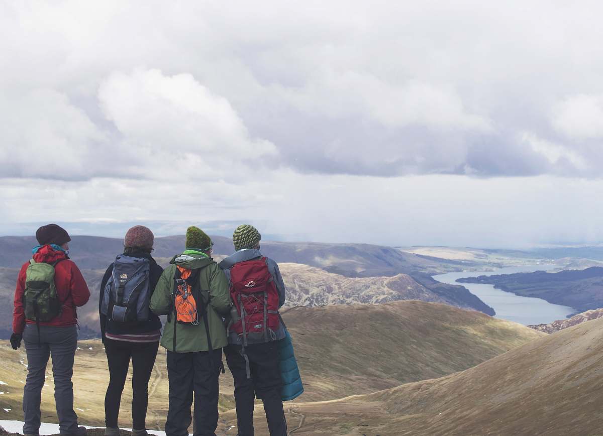 person four person standing while looking on mountain view with body of water at daytime view