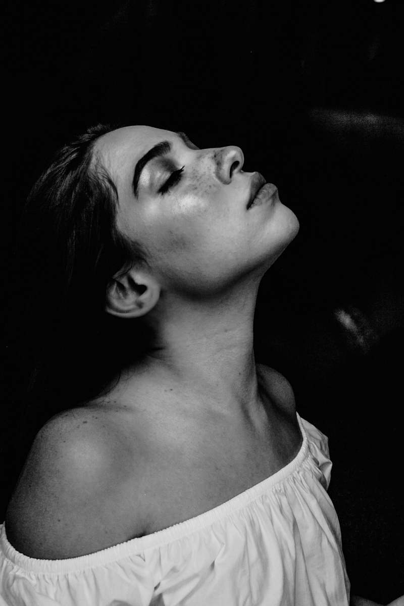 black-and-white grayscale photo of a woman wearing white off-shoulder shirt portrait