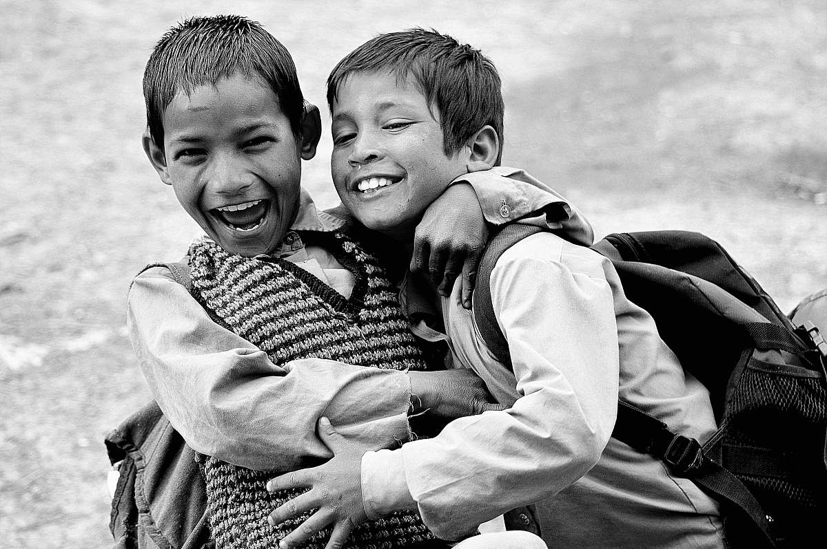 human grayscale photography of two boys hugging while laughing black-and-white