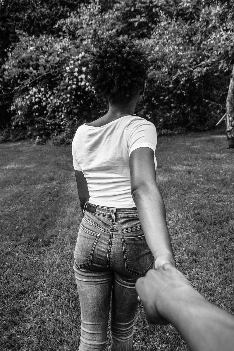 black-and-white greyscale photography of woman walking with hand at the back holding other hand woman