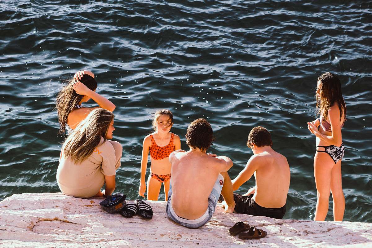 person group of kids having a conversation near body of water family