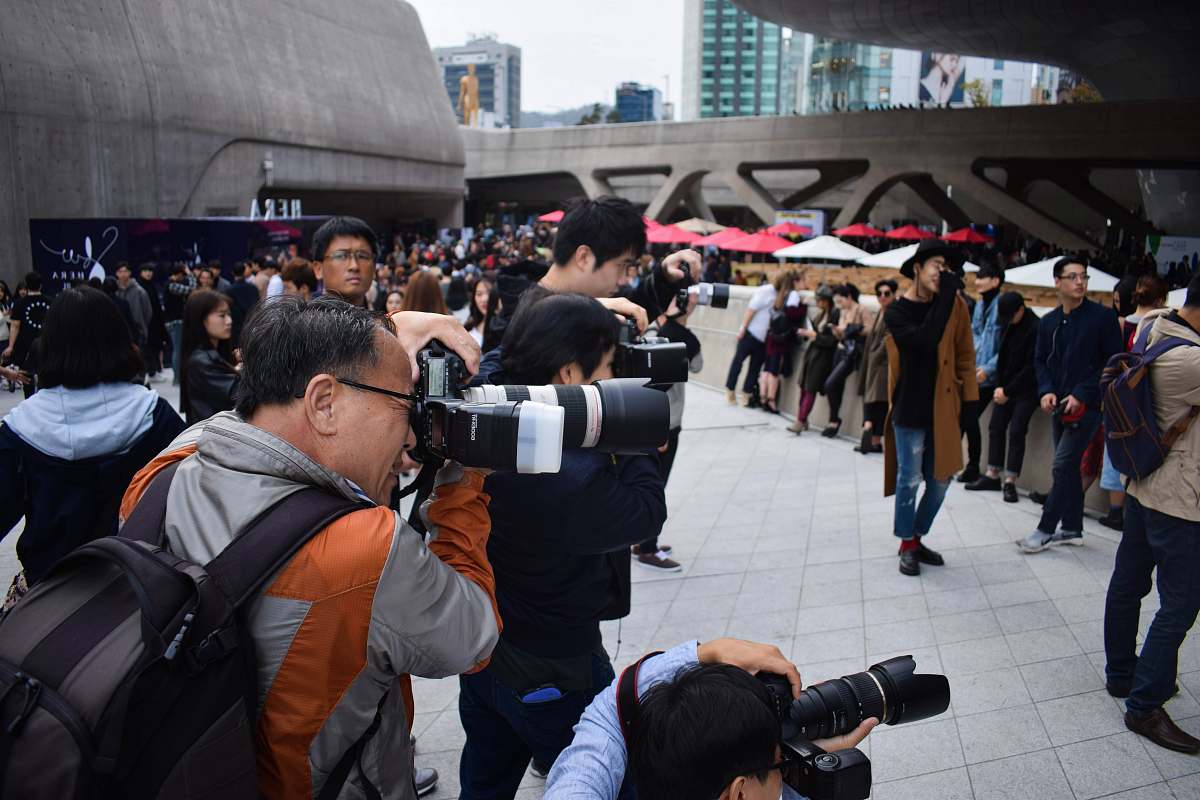photographer group of photographers holding DSLR cameras in event during daytime crowd