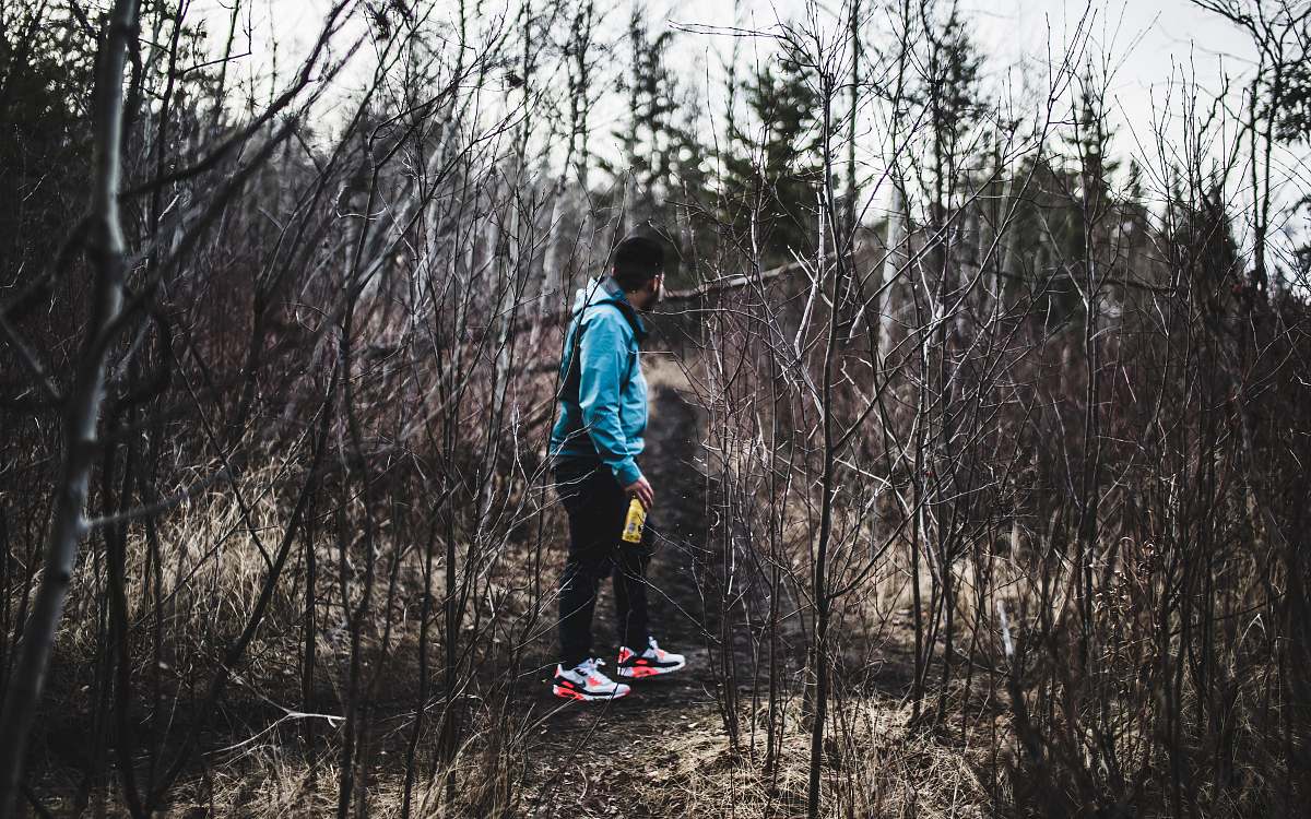 person man in blue jacket and black pants in woods human
