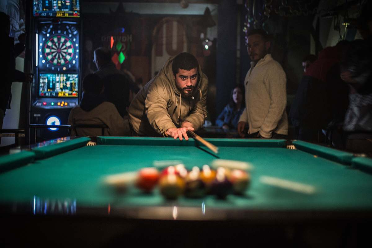 person man in brown jacket playing billiard table