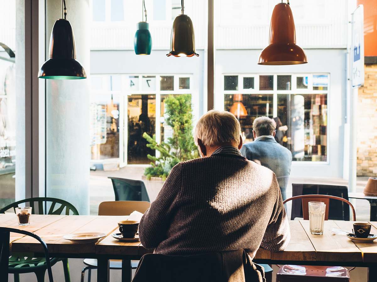 person man in chair with table beside coffee cafe