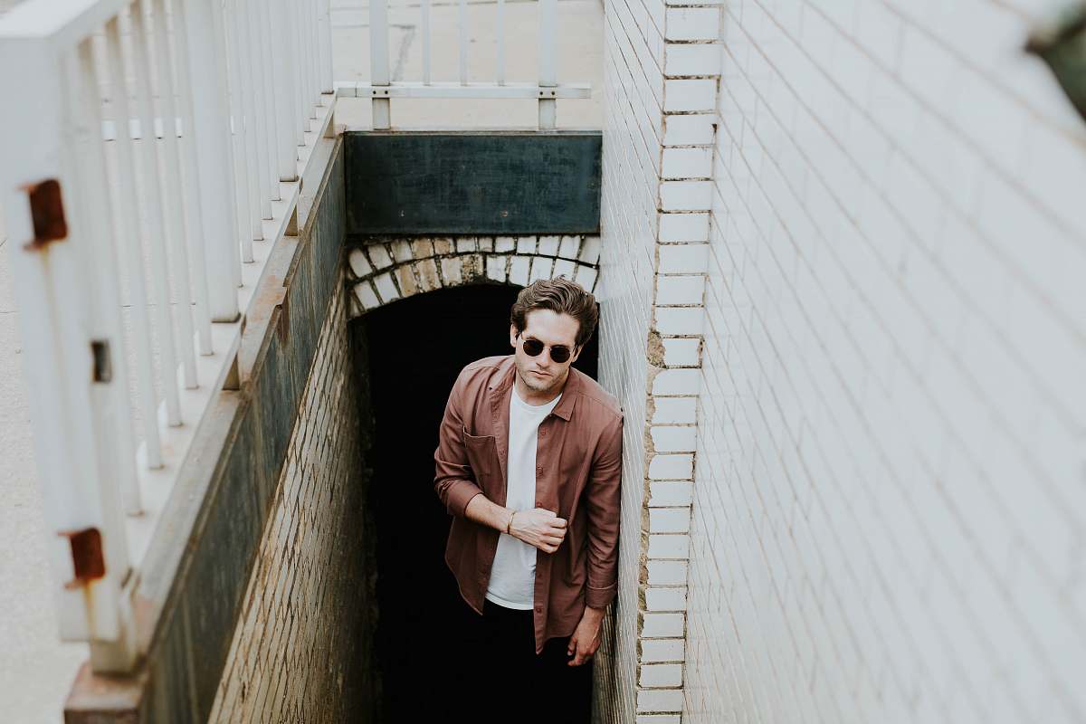 person man leaning on wall while standing on stairs underground human