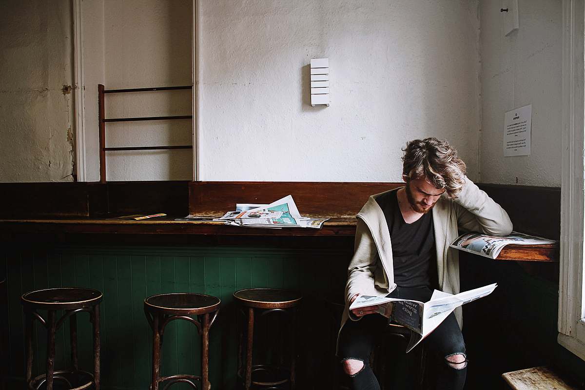 person man sitting on bar stool while holding newspaper bar stool