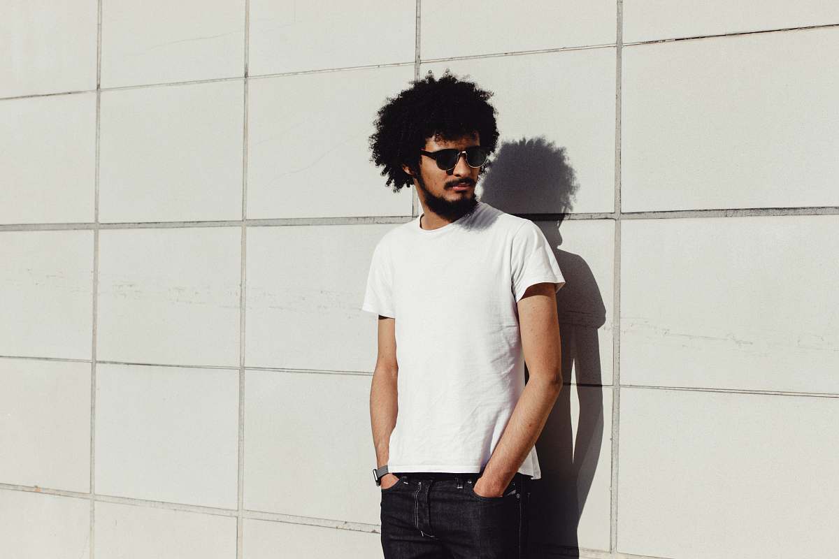 person man standing near white wall during daytime human