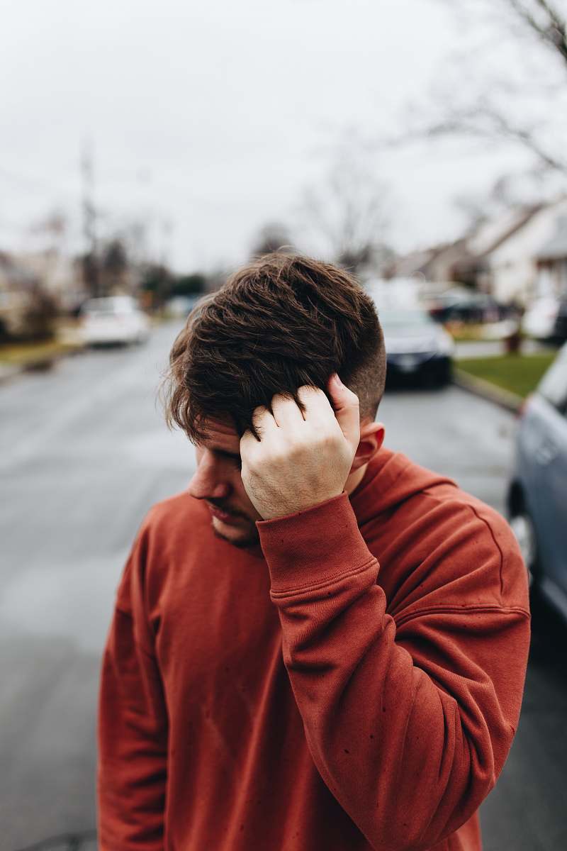 person man walking on road with left hand on head human