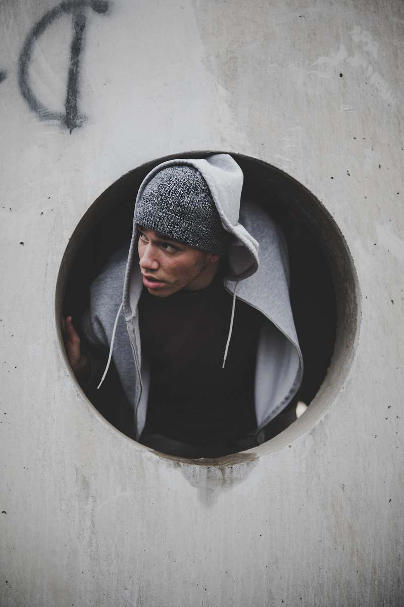 person man wearing black shirt and knit cap with hoodie jacket inside concrete hole human