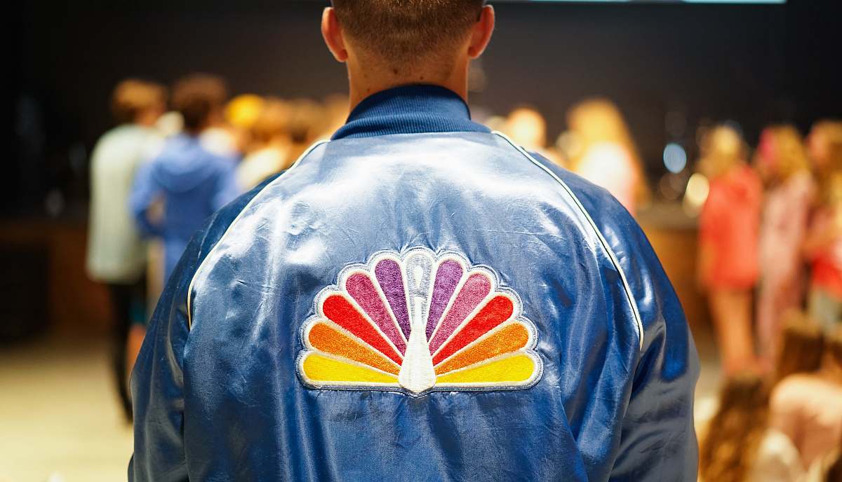 person man wearing blue jacket standing in front of people human