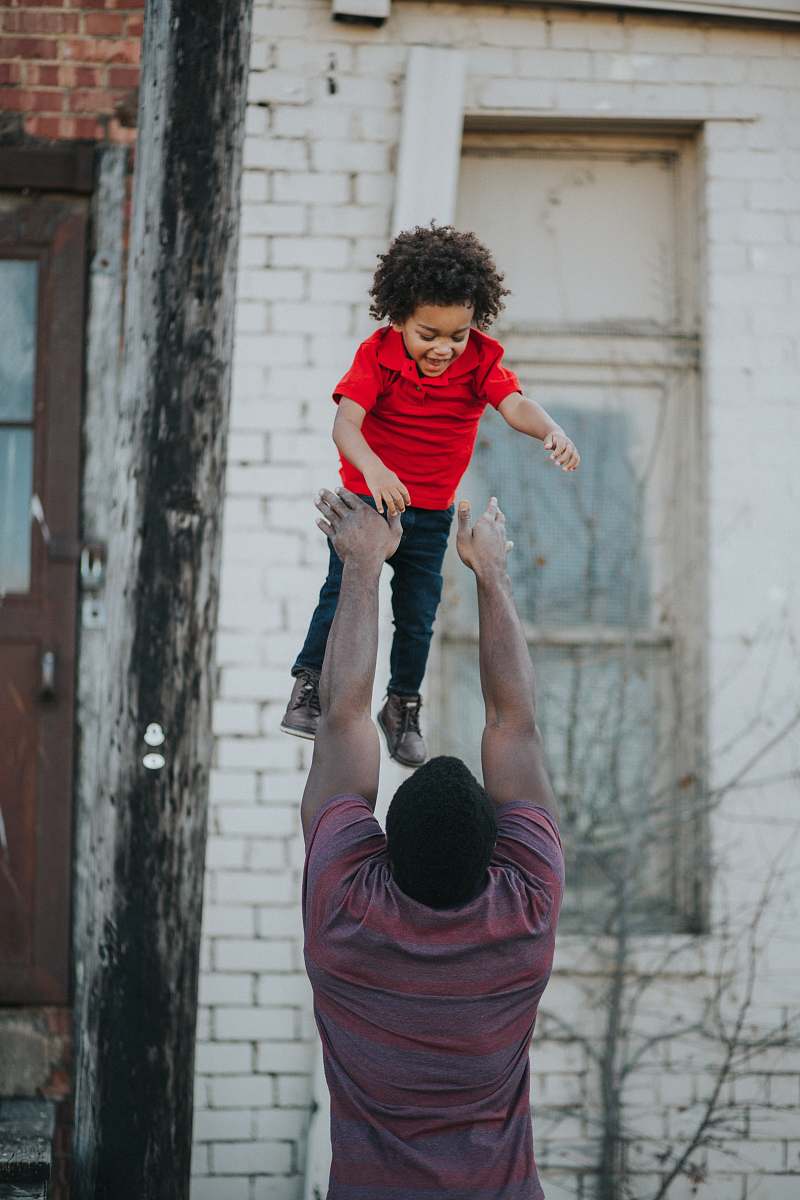 human man wearing purple and red shirt catching child wearing red shirt person