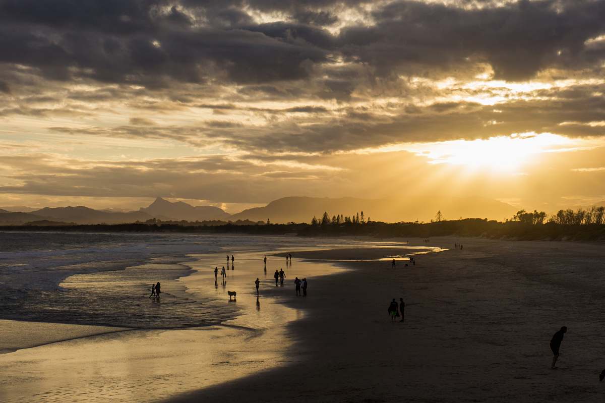 sky people on seashore during golden hour clouds