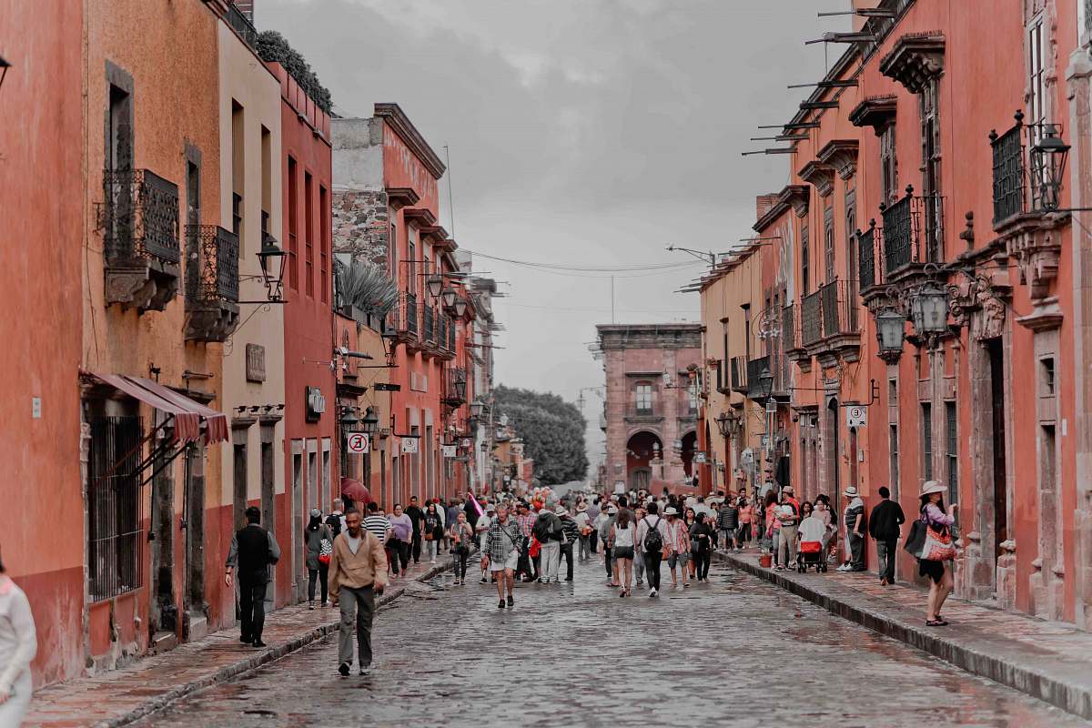 mexico people walking between orange concrete buildings urban