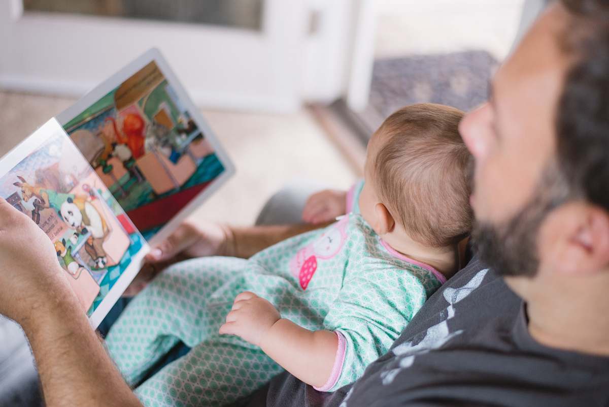 reading person carrying baby while reading book baby