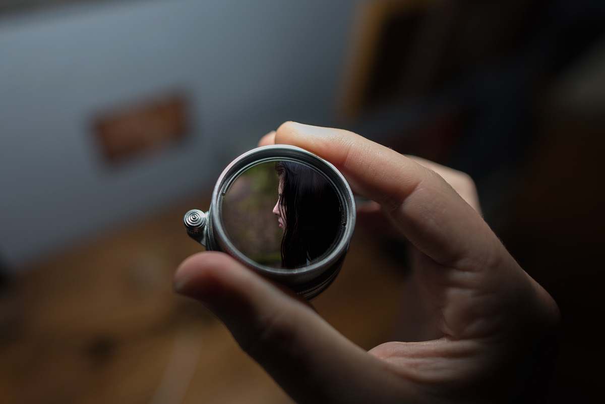 person person holding round grey mirror selective focus photography human