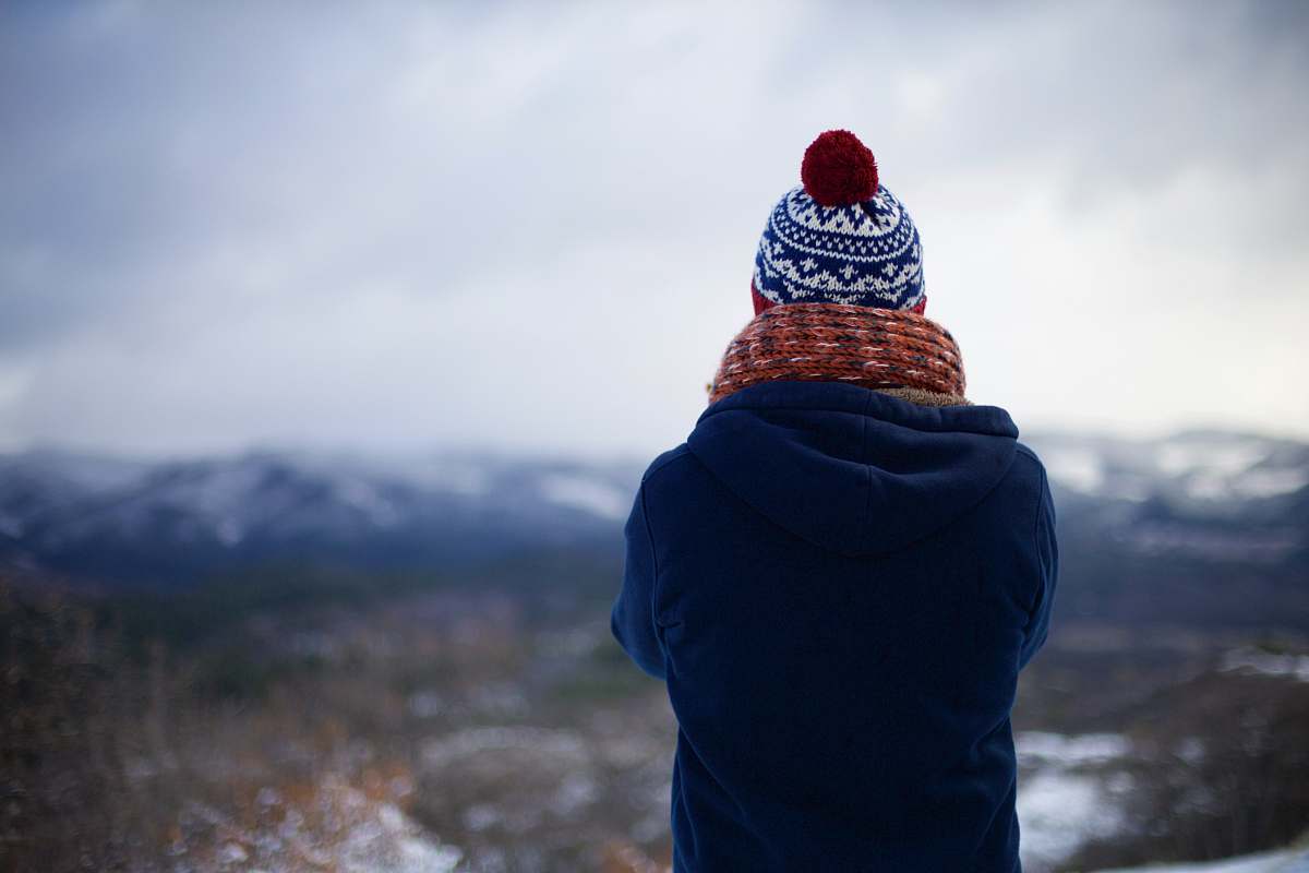 person person wearing blue hoodie facing mountains nature