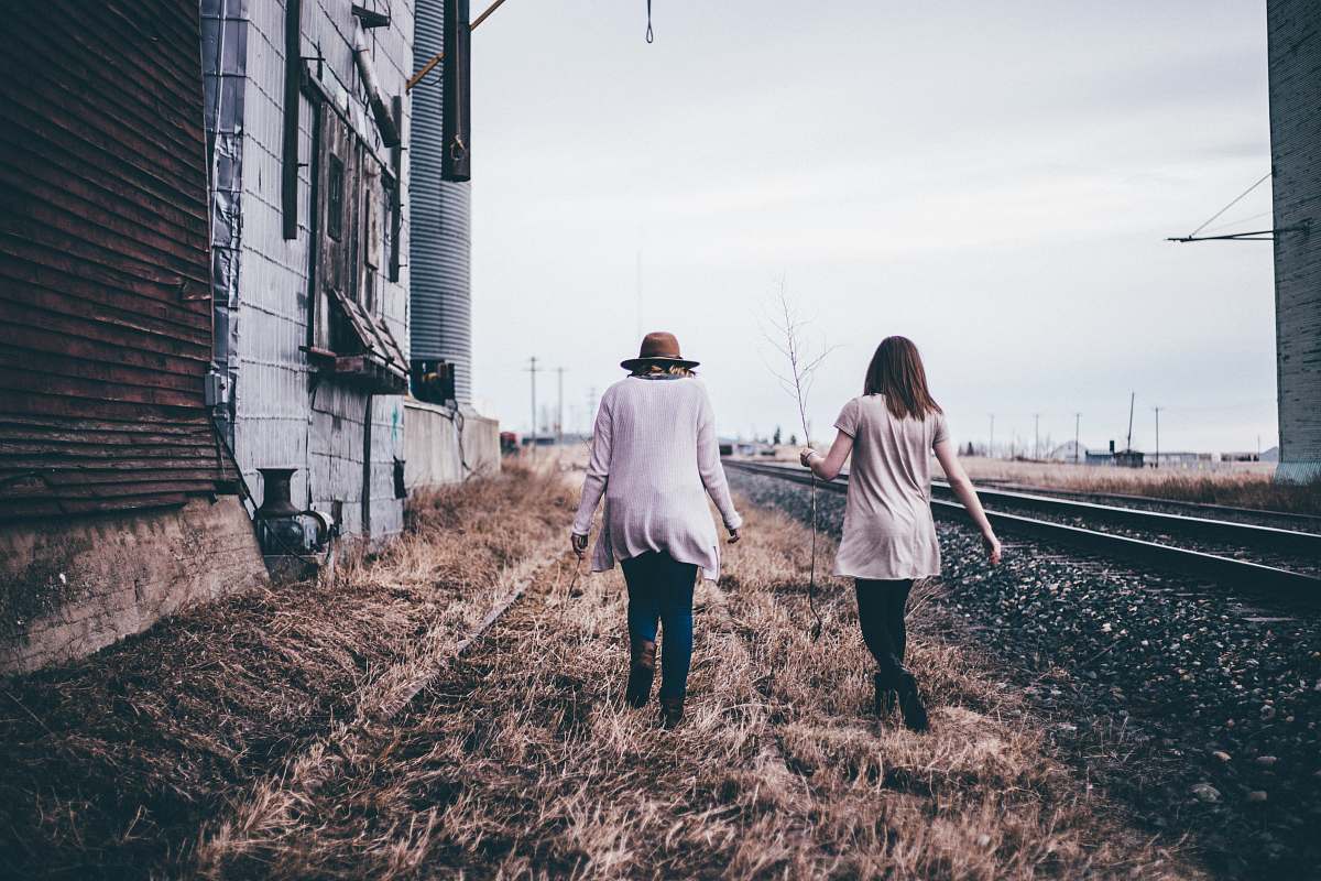 person photo of two persons walking along railway human