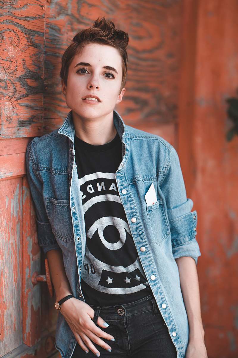person portrait photography of woman leaning beside on brown wooden wall human