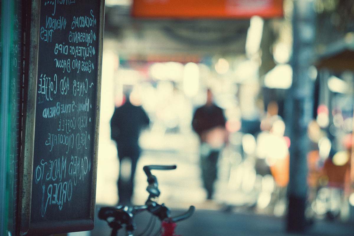 person red and gray bicycle parked near black chalkboard with menu writing selective focus photography blackboard