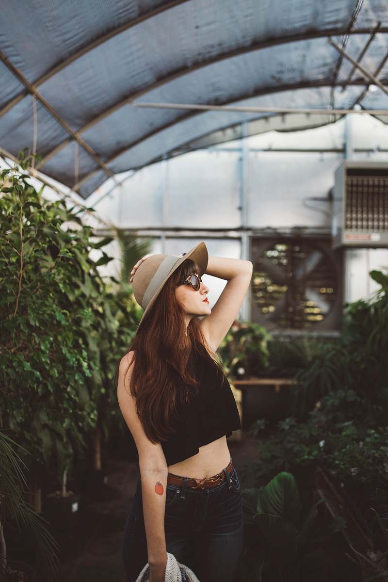 sunglasses shallow focus photography of woman posing while holding her hat at the garden plant