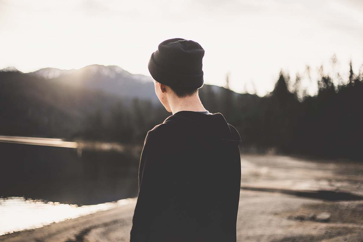 person tilt shift lens photography of man standing near body of water human