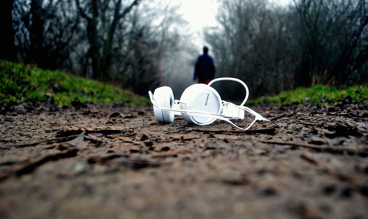 person tilt shift lens photography of white corded headphones forest