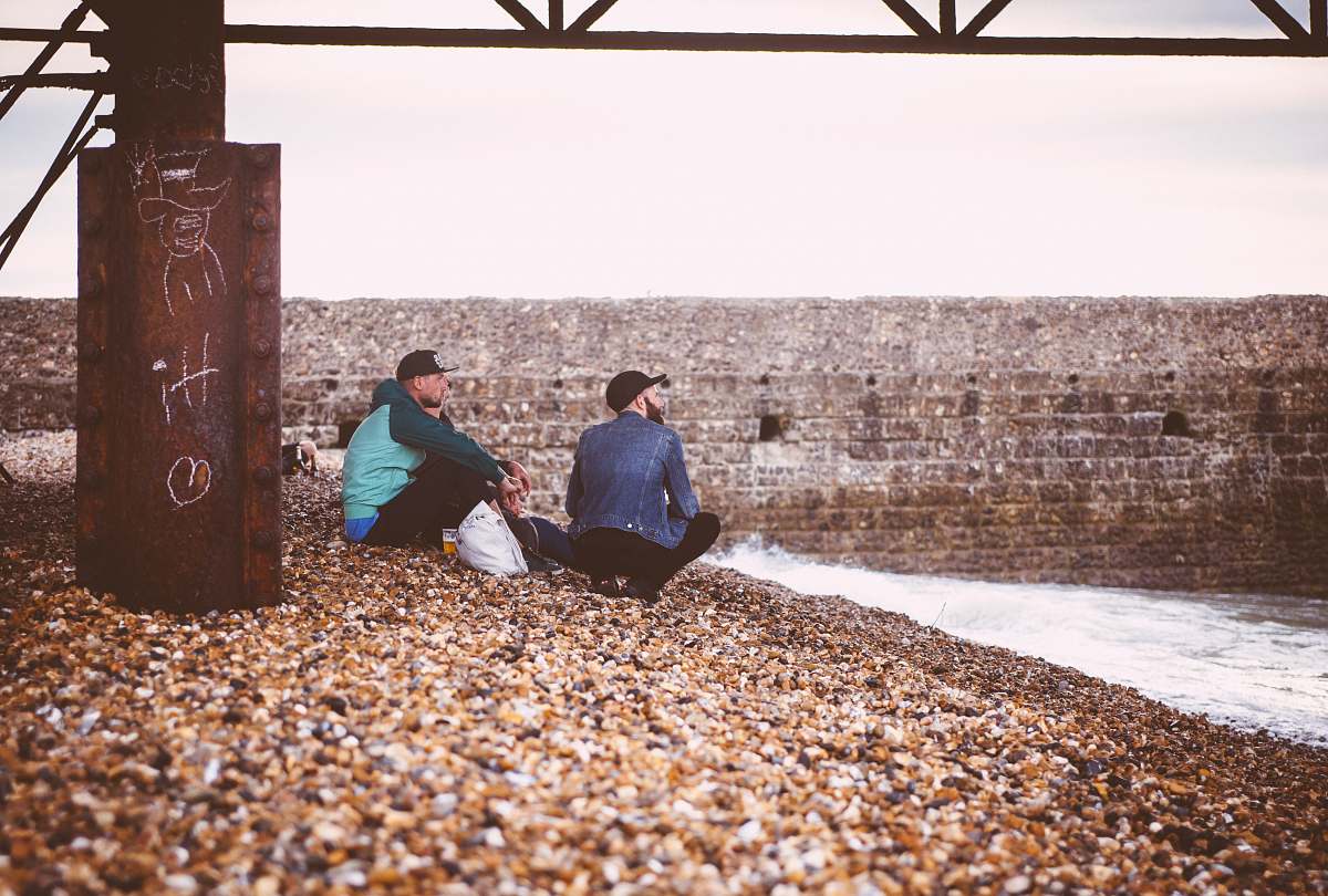 man two men sitting near body of water male
